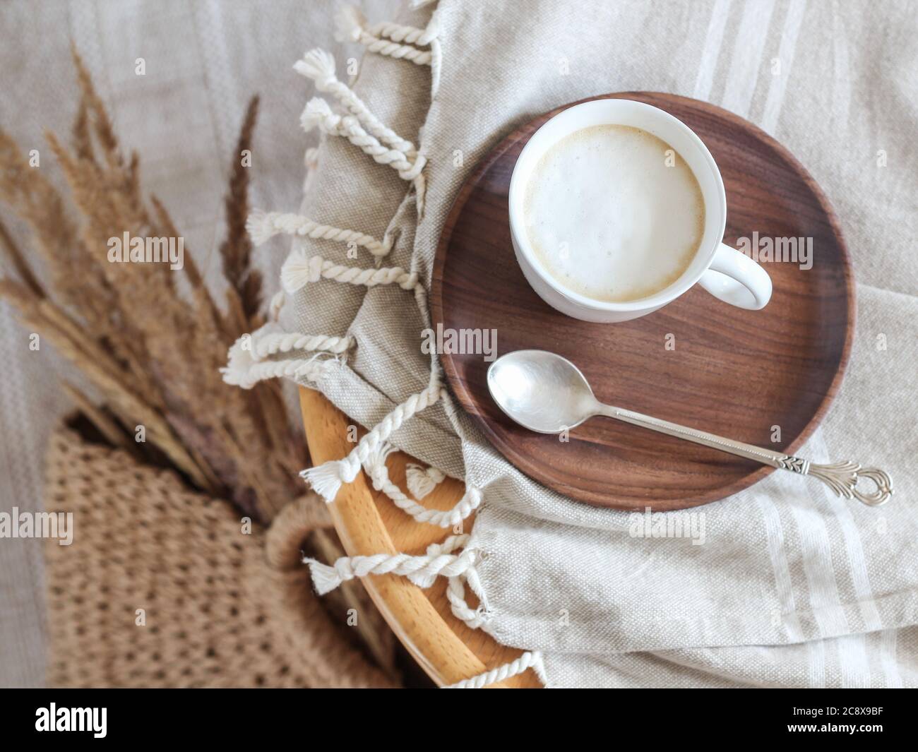 Una tazza di caffè con latte su un piatto di legno e bentgrass secchi in un cesto Foto Stock