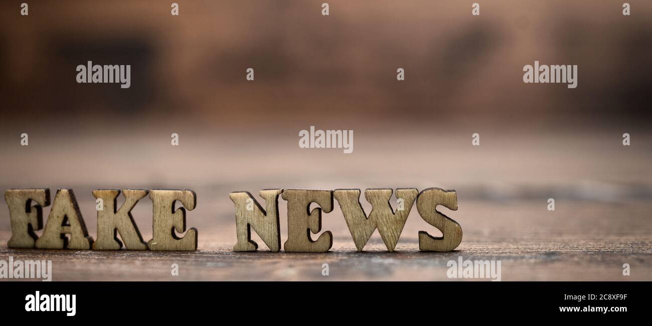 Notizie false lettere in legno su sfondo legno. Notizie false come una forma di notizie che consiste di disinformazione deliberata o hoax sparsi attraverso il tradizionale Foto Stock