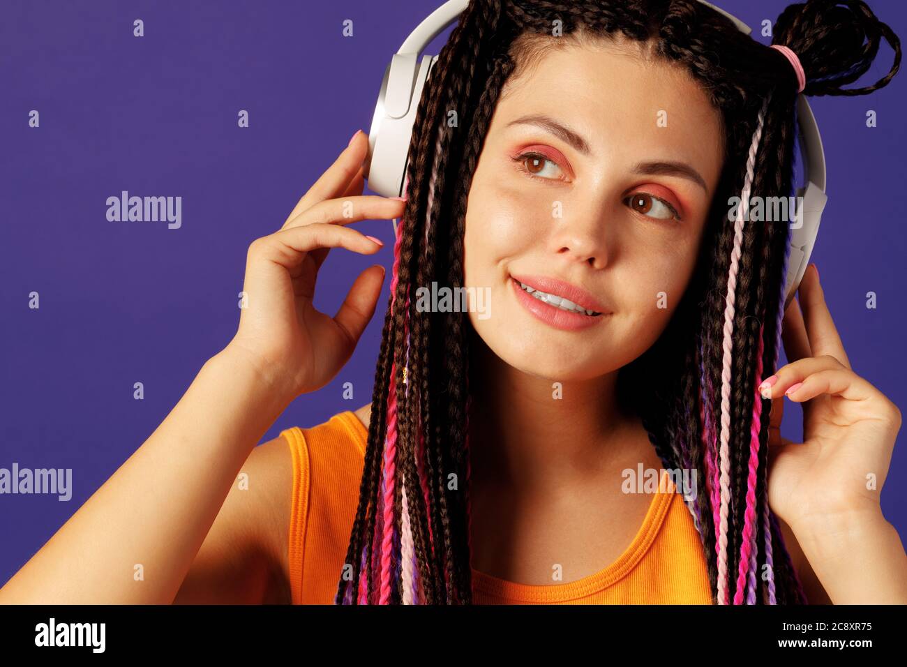 Giovane caucasica con cornrows africani che ascolta musica con le cuffie Foto Stock