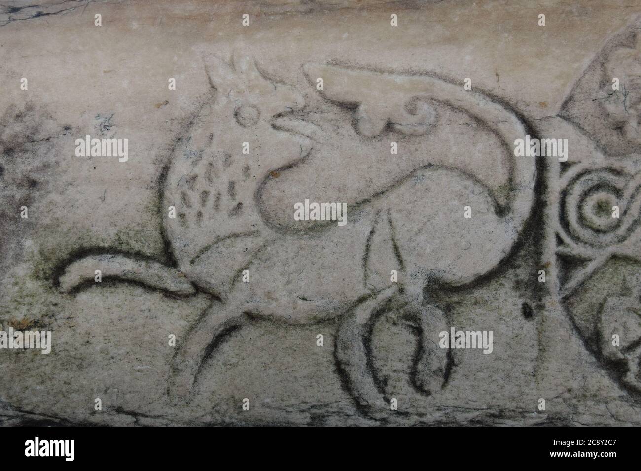 Scultura in pietra del cane da caccia o creatura mitologica sull'antica colonna di marmo di agora. Foto Stock