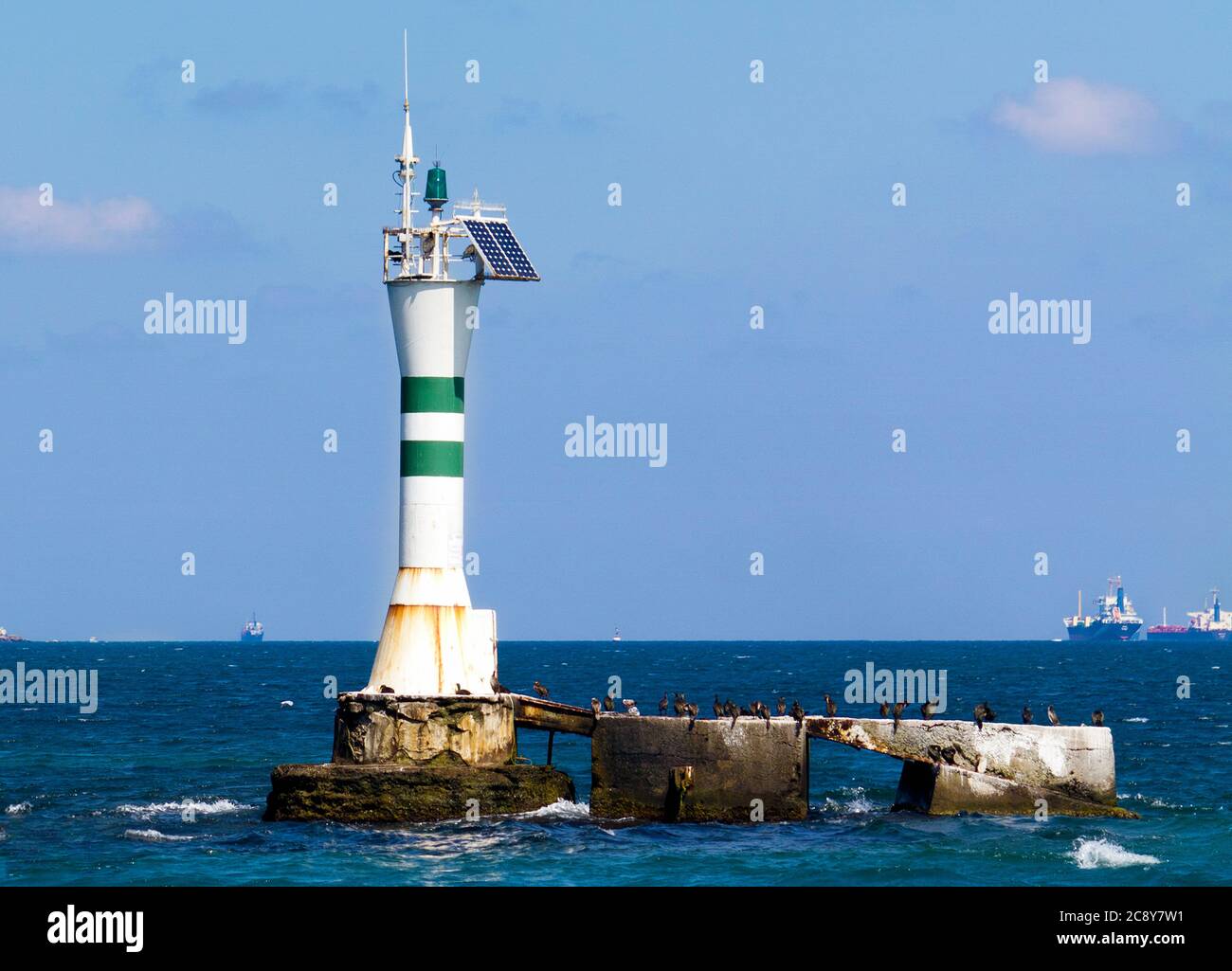 Faro con energia solare, e vista in lontananza dalle grandi barche Foto Stock