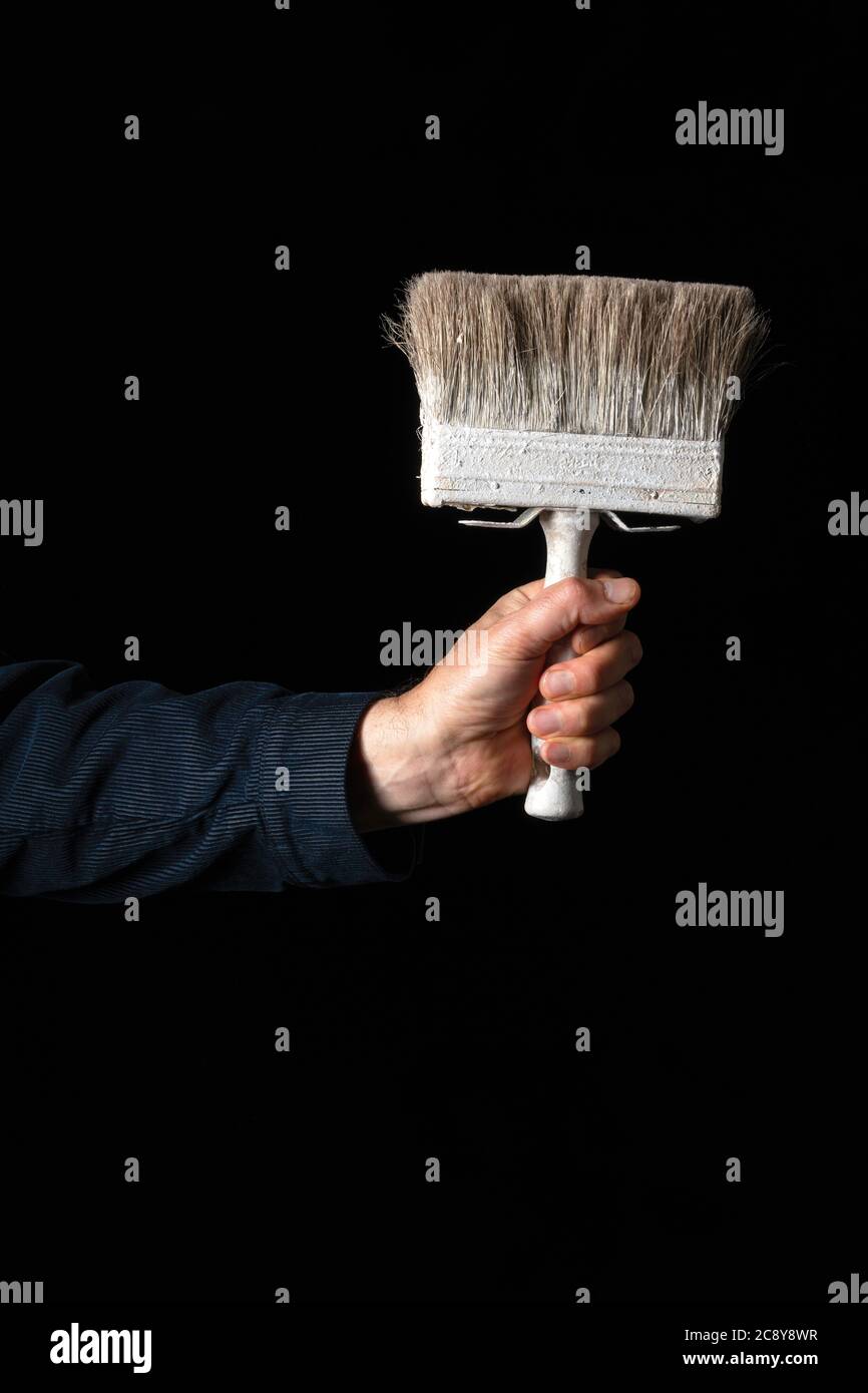 Primo piano di uomo che tiene la spazzola di vernice su sfondo scuro Foto Stock