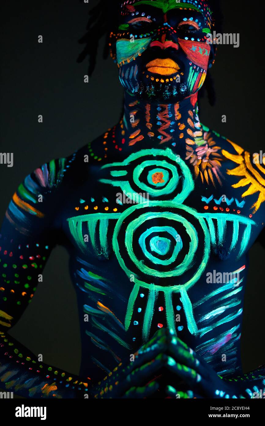 Ritratto concettuale di un giovane africano dipinto in colori UV  fluorescenti incandescenti. Make-up, body art concept, isolato studio shoot  Foto stock - Alamy