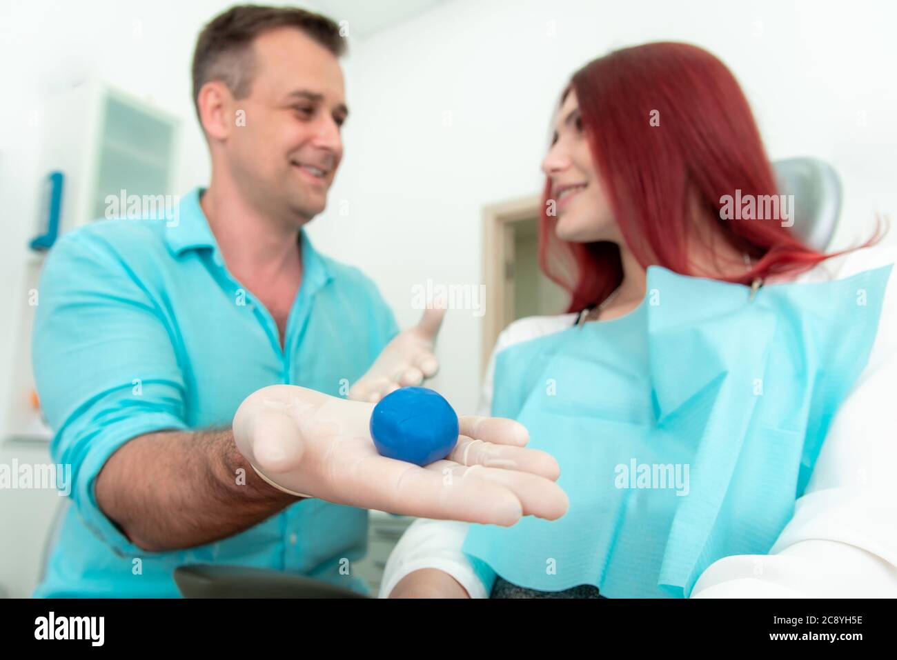 Il dentista sgretola il materiale siliconico per il vassoio per impronte da posizionare nella bocca del paziente per modellare i denti. Foto Stock