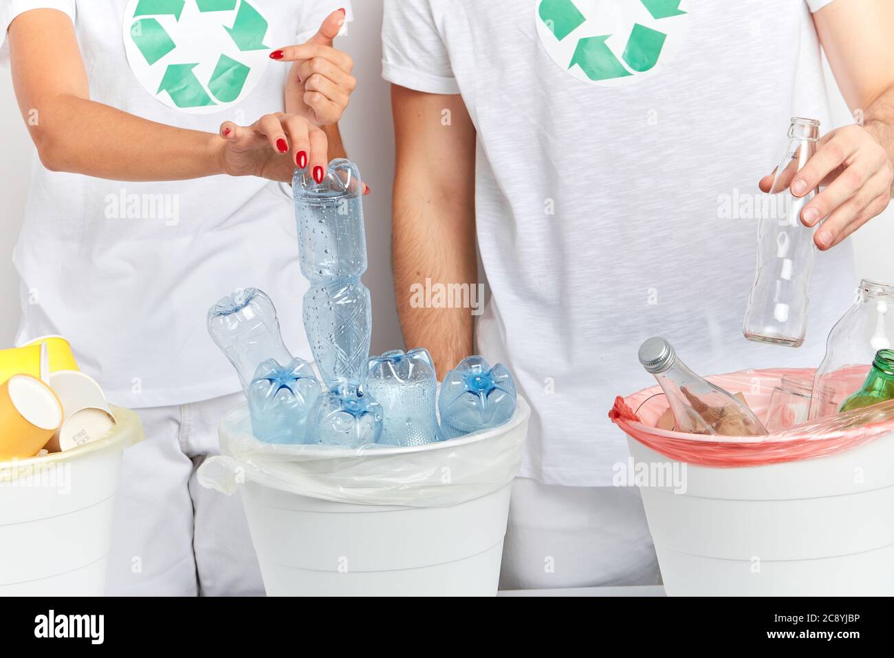 i volontari mettono gli oggetti che possono essere riciclati nei contenitori corretti. primo piano ritratto, studio shot, coppia scegliendo plastica e vetro per metterli int Foto Stock