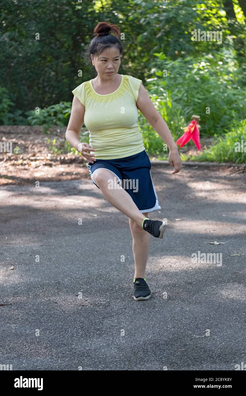 Una donna gioca a Jianzi, uno sport cinese tradizionale in cui i giocatori puntano a mantenere un peso pesante shuttleock in aria utilizzando il loro corpo. Foto Stock