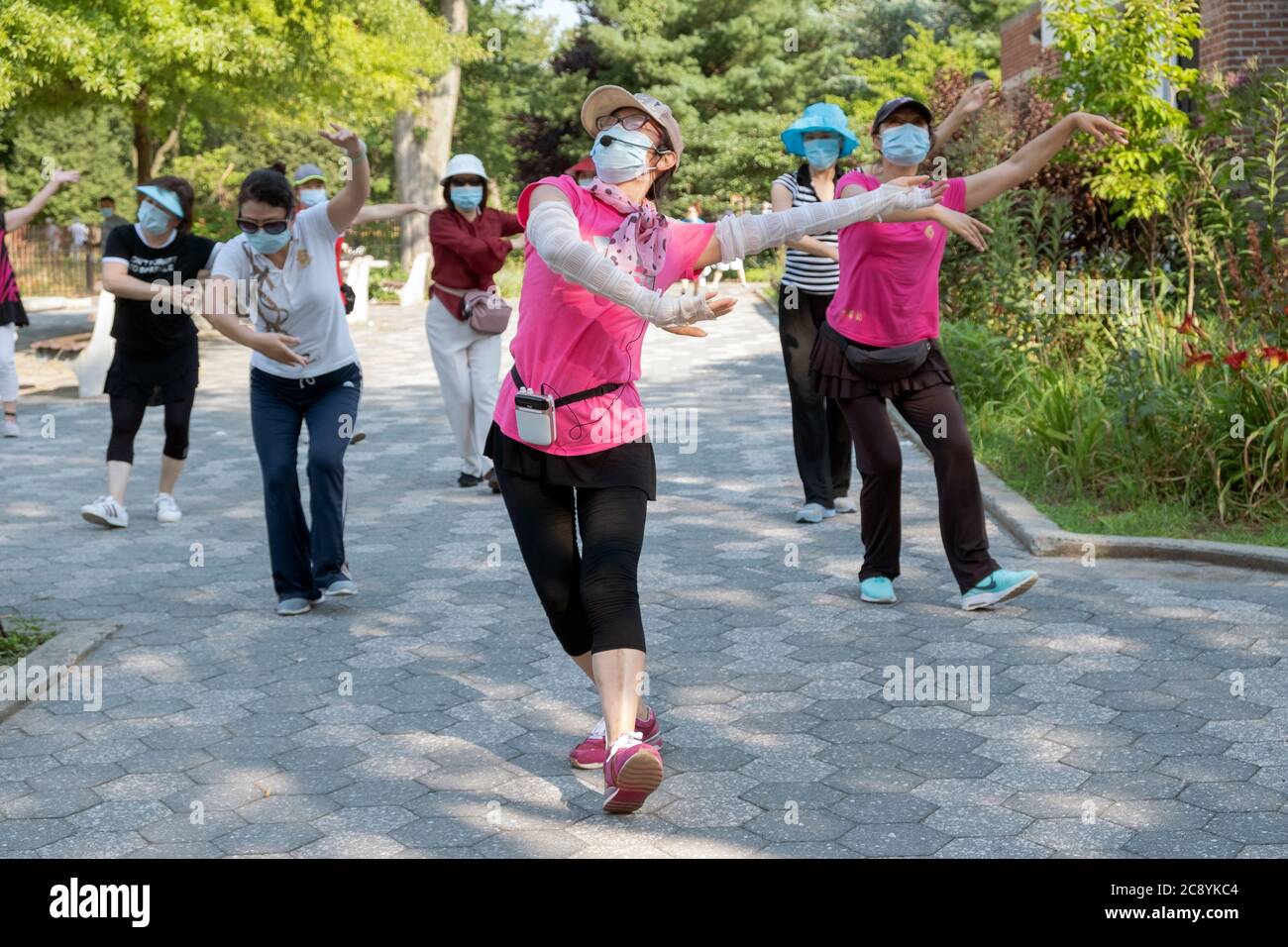 Indossando maschere e osservando la distanza, un gruppo di donne cinesi americane pratica la danza cinese moderna. A Flushing, Queens, New York City Foto Stock