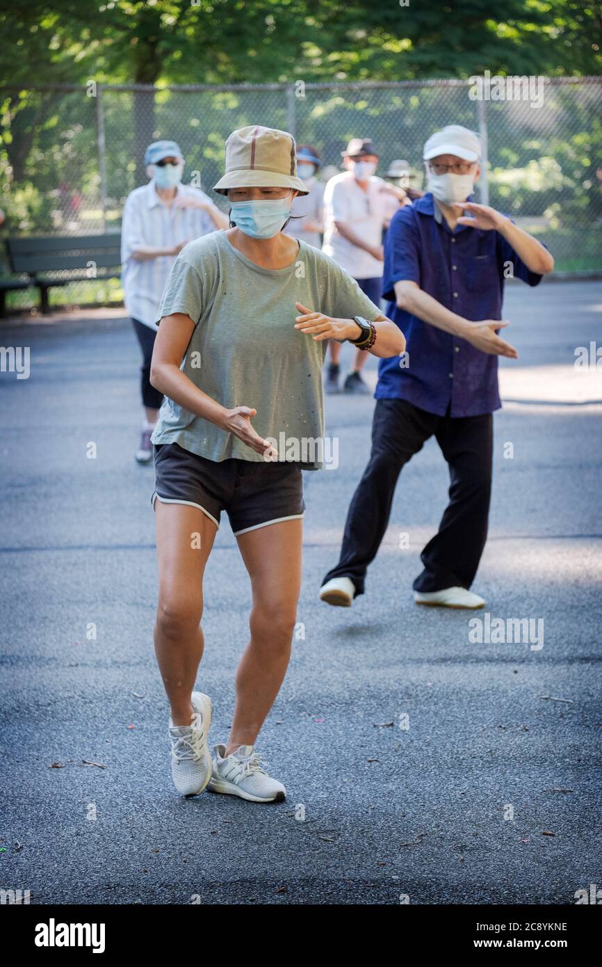 Uomini e donne di varie età ed etnie frequentano una lezione di Tai Chi al mattino indossando maschere chirurgiche e divaricatori sociali. In Queens, New York City. Foto Stock