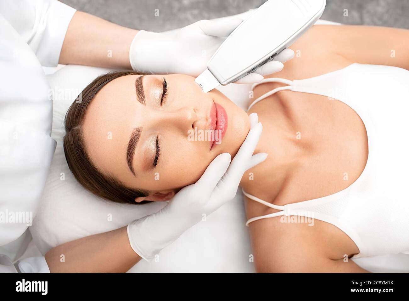 Donna che ottiene pelle di buccia ultrasonica, una procedura di pulizia utilizzando un dispositivo speciale. Procedura di peeling a ultrasuoni e pulizia del viso primo piano Foto Stock