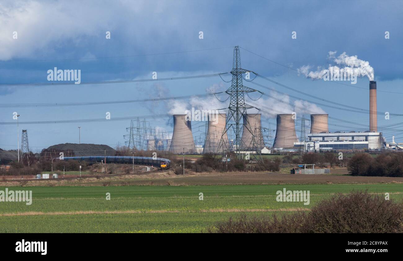 BC Cargo rail classe 66 locomotiva che trasporta un treno di carri Drax Biomass oltre le torri di raffreddamento della centrale a carbone Eggborough e la collisione di Kellingley Foto Stock