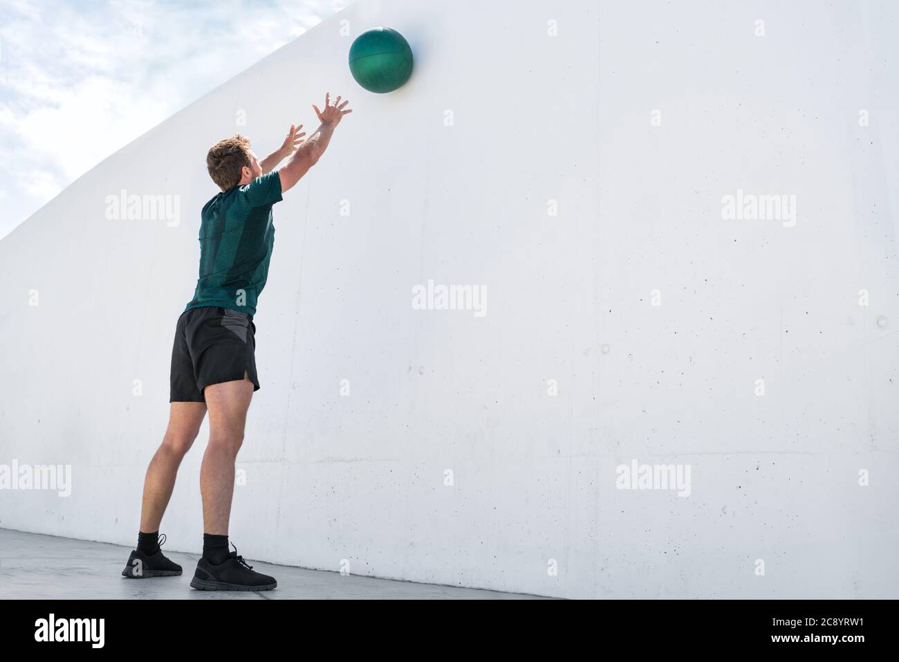 Fitness uomo gettando palla di medicina sulla parete palestra Foto Stock