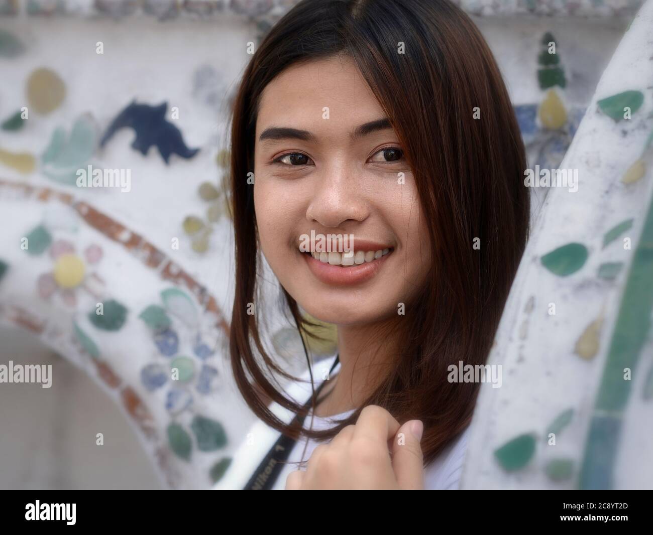 Bella ragazza tailandese sorride per la macchina fotografica al tempio Wat Arun di Bangkok. Foto Stock