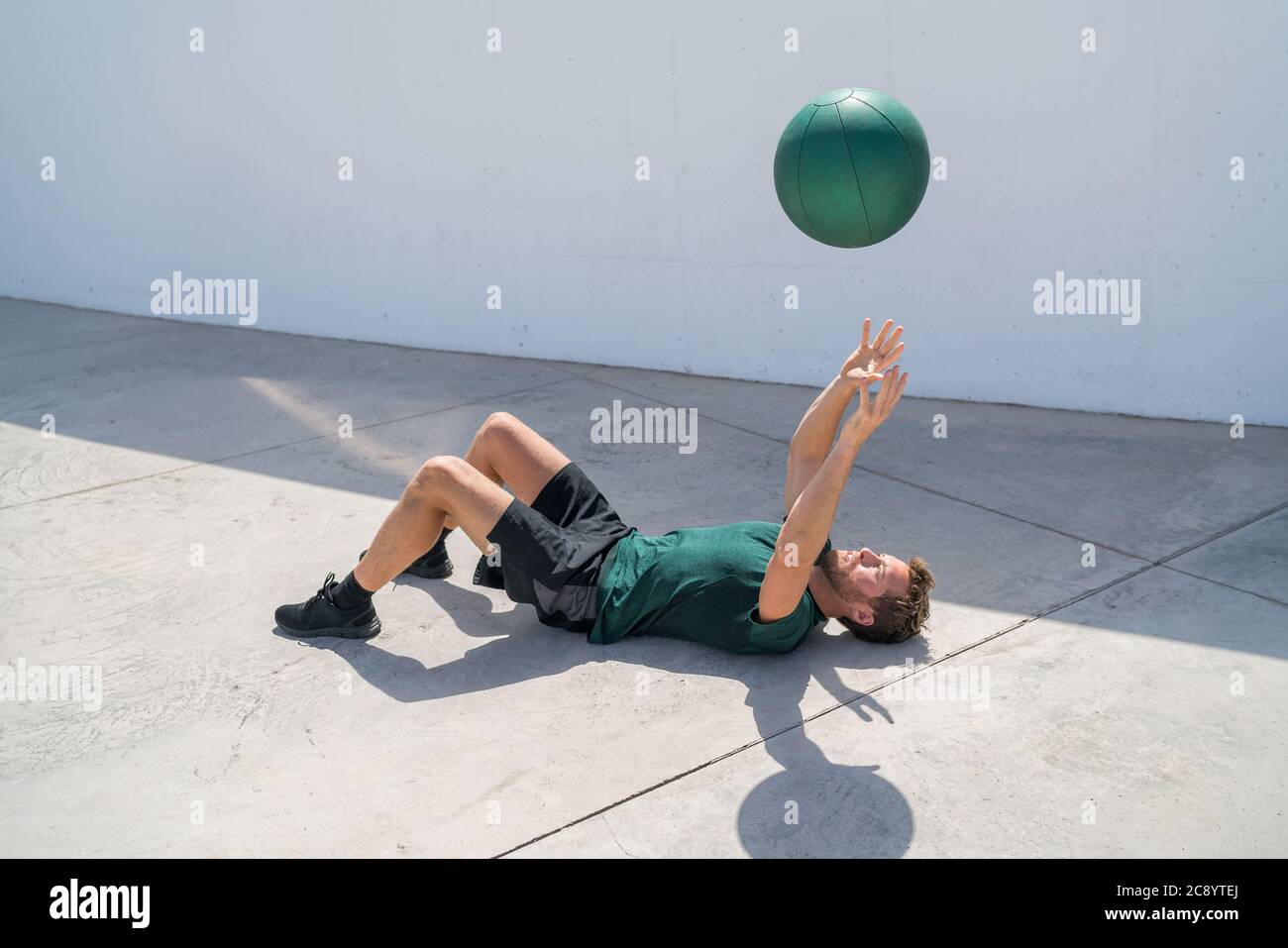 Uomo di addestramento che getta la palla di medicina nell'aria Foto Stock