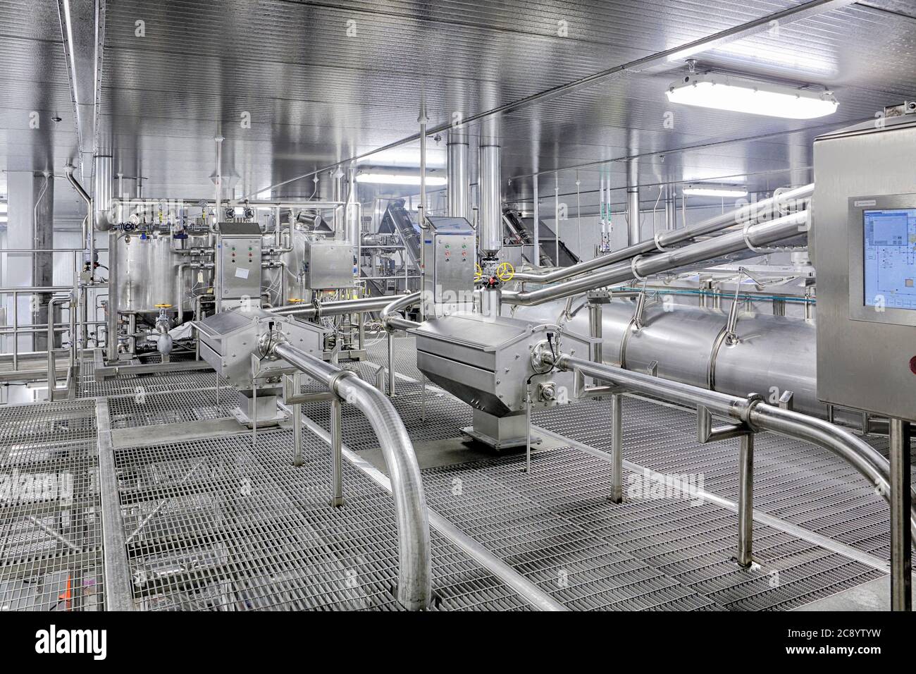 Nuovi macchinari industriali in acciaio inox con pannelli di controllo in un impianto commerciale di lavorazione degli alimenti. Foto Stock