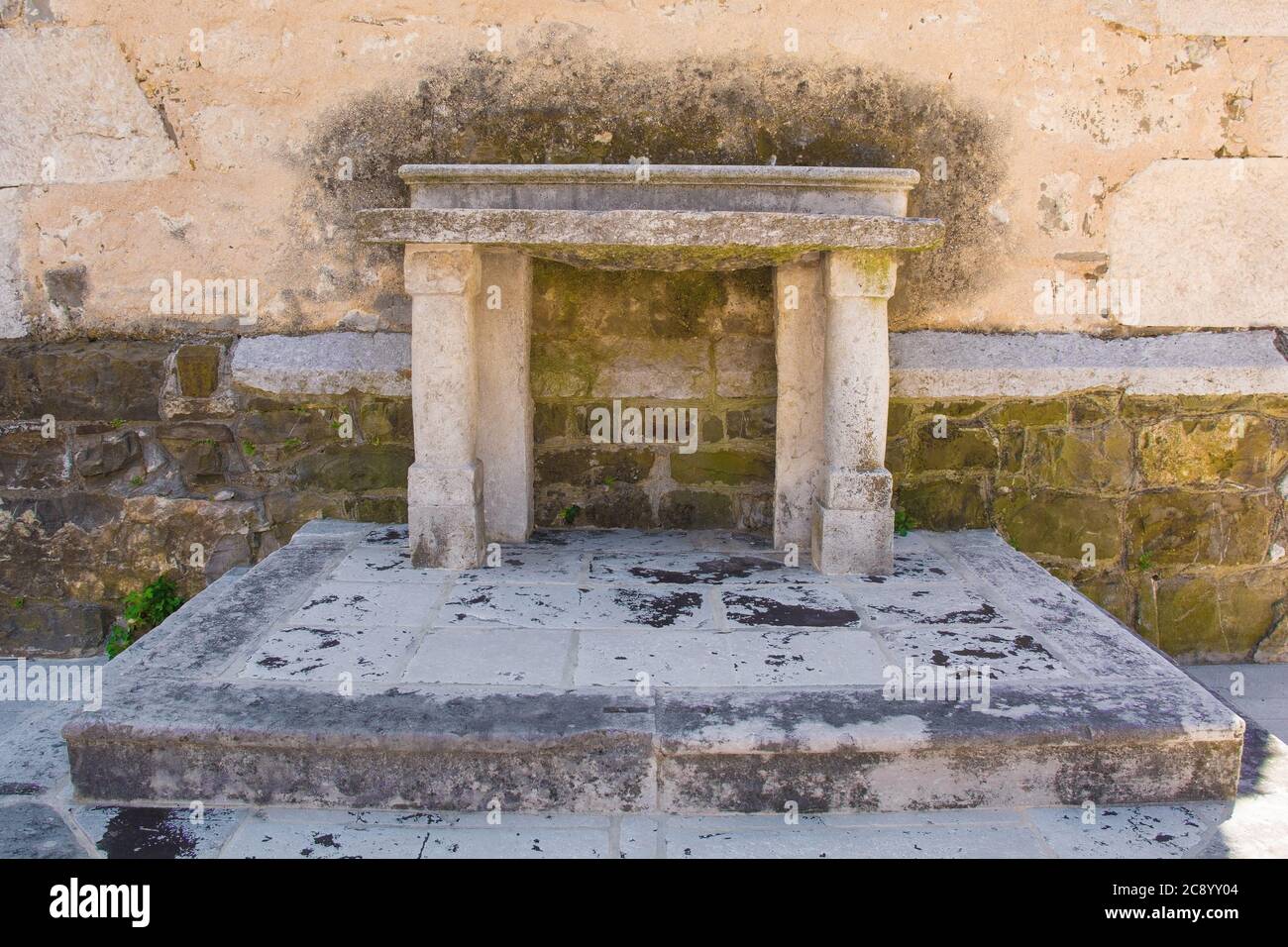 Un altare storico in pietra accanto al campanile della chiesa parrocchiale di San Vito nel villaggio di Podnanos, Valle di Vipava, comune di Vipava, Primorska, Slovenia Foto Stock