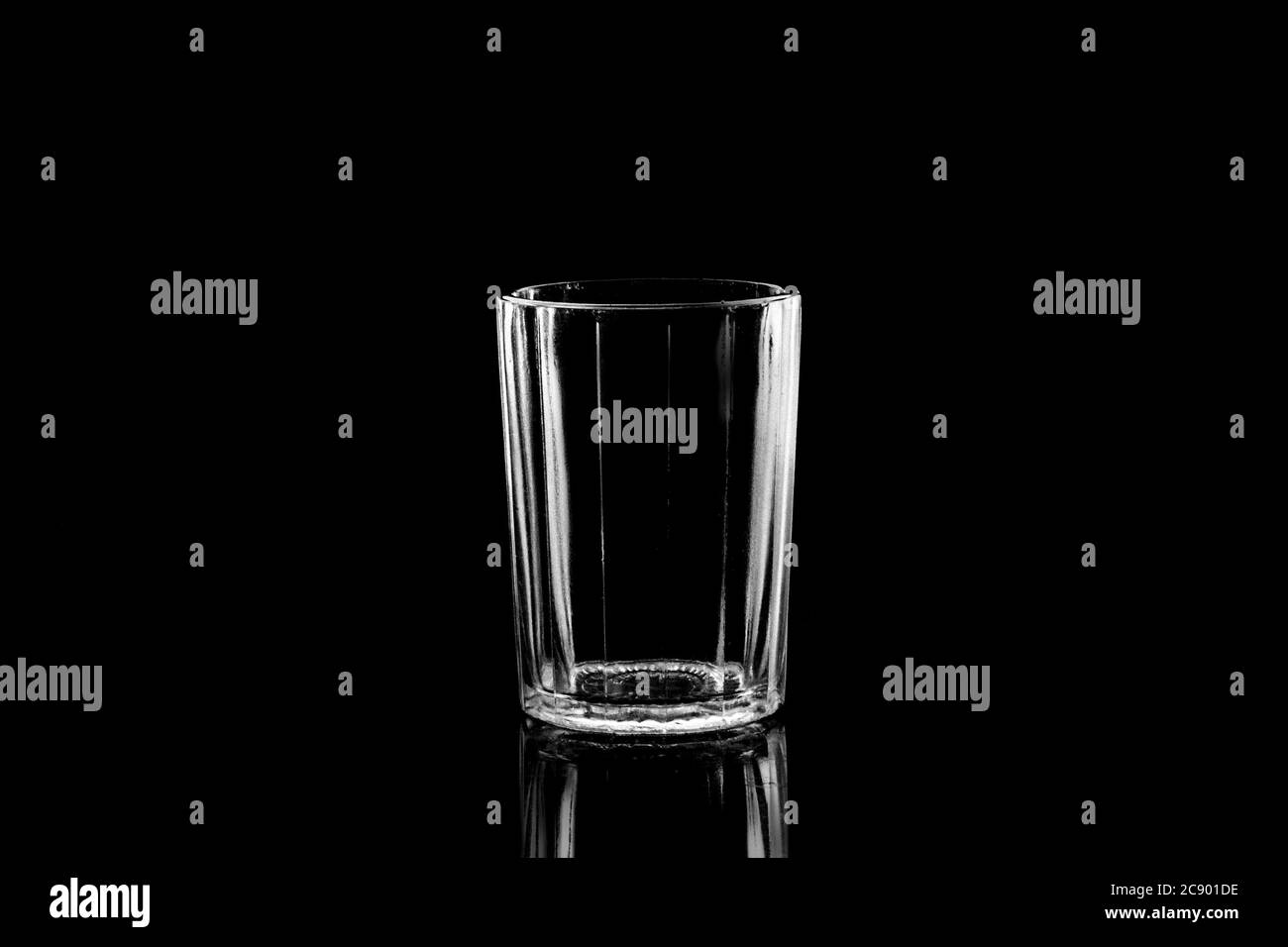 Low-key Studio Shot di una silhouette bianca di un vetro sfaccettato vetri luce isolato su uno sfondo nero. Linee e forme uniformi. Concetto. Foto Stock