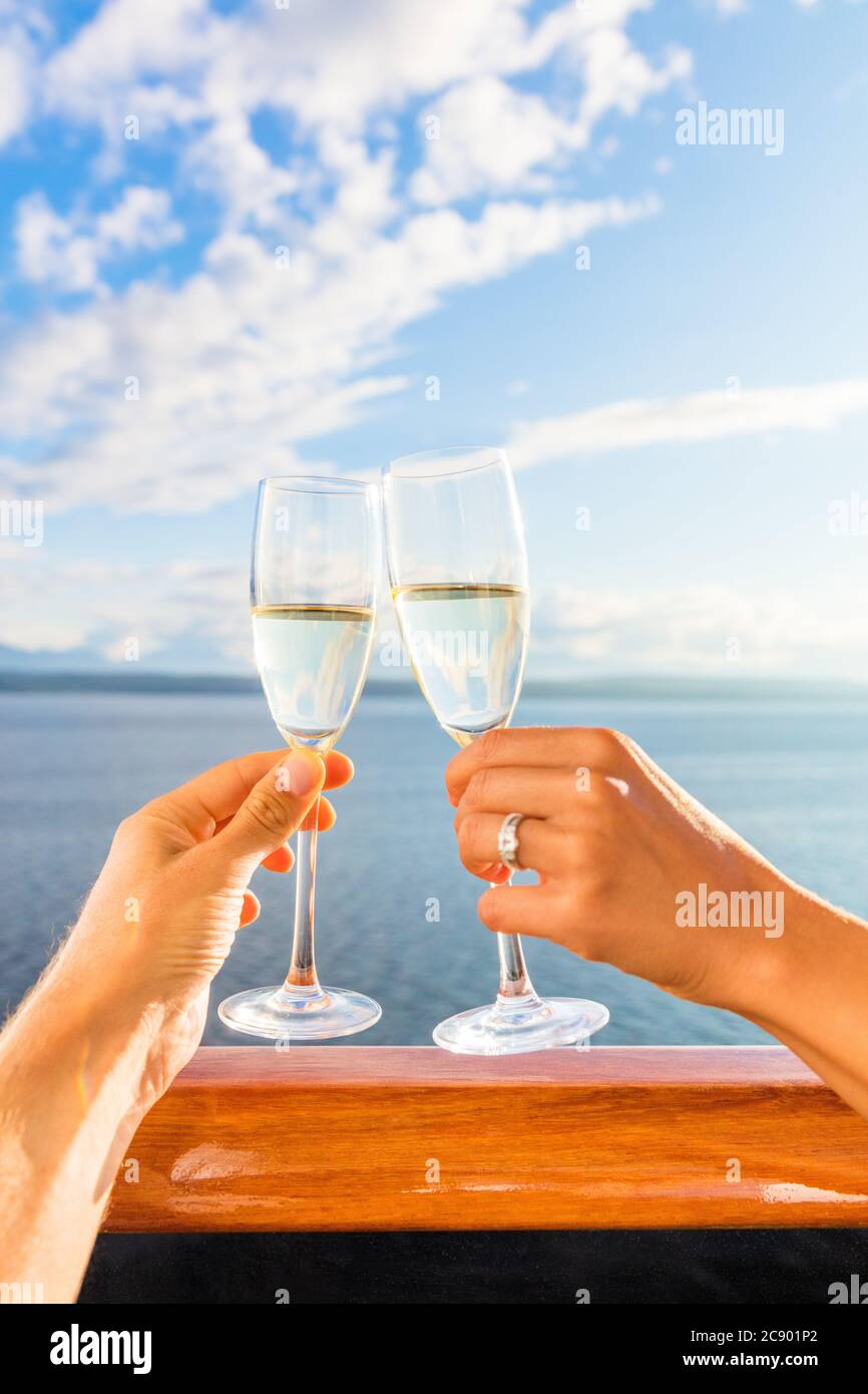 Crociera di lusso per coppie in luna di miele con degustazione di champagne. Viaggi vacanza sposi che bevono con gli anelli di nozze che tengono i vetri che fanno le grazie alla vista del tramonto di Foto Stock