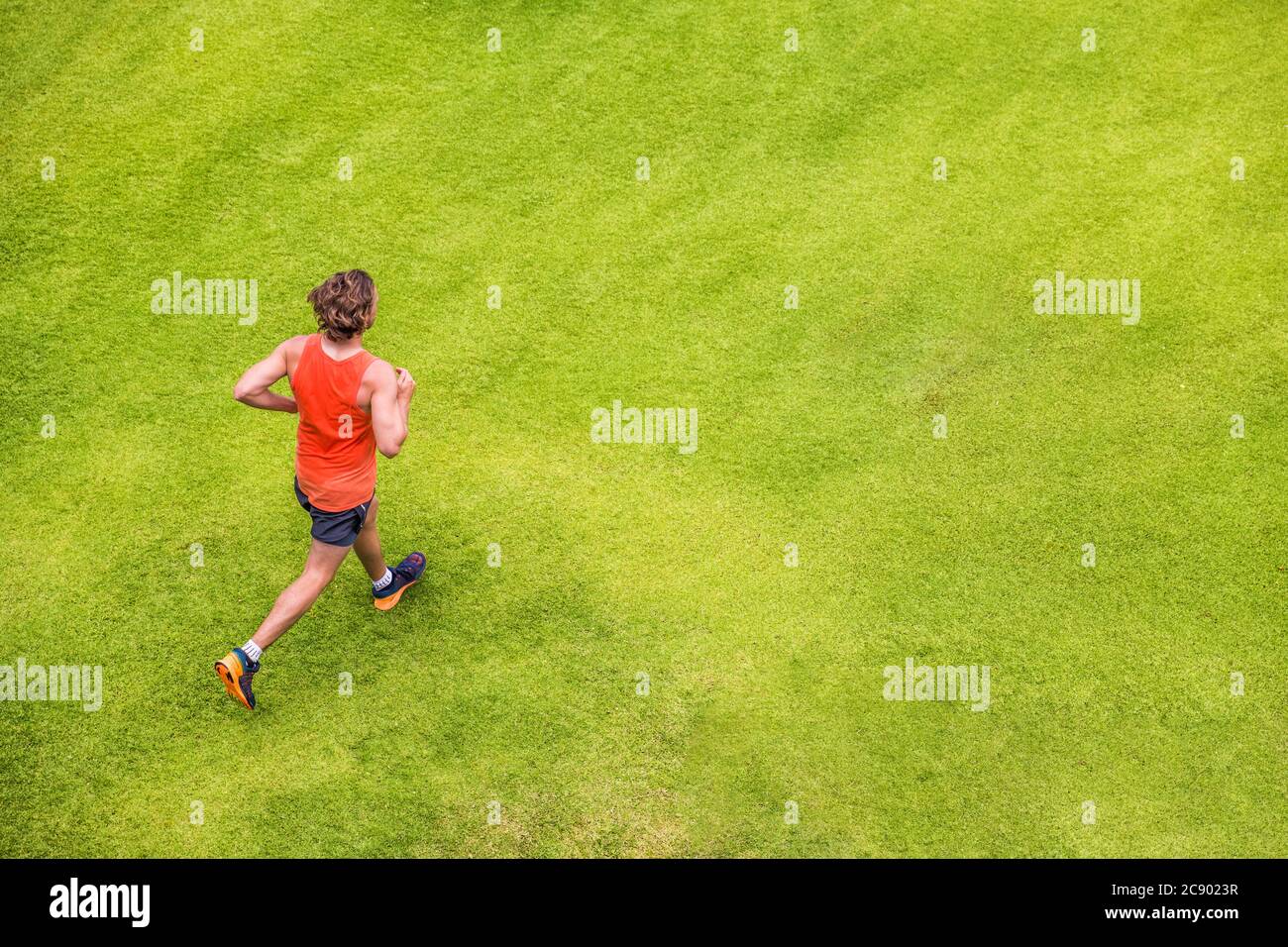 Runner man che corre sull'erba estate parco jogging sano stile di vita. Persone che lavorano in vista dall'alto cardio. Copia spazio su sfondo texture verde Foto Stock