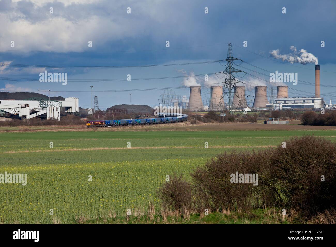 BC Cargo rail classe 66 locomotiva che trasporta un treno di carri Drax Biomass oltre le torri di raffreddamento della centrale a carbone Eggborough e la collisione di Kellingley Foto Stock
