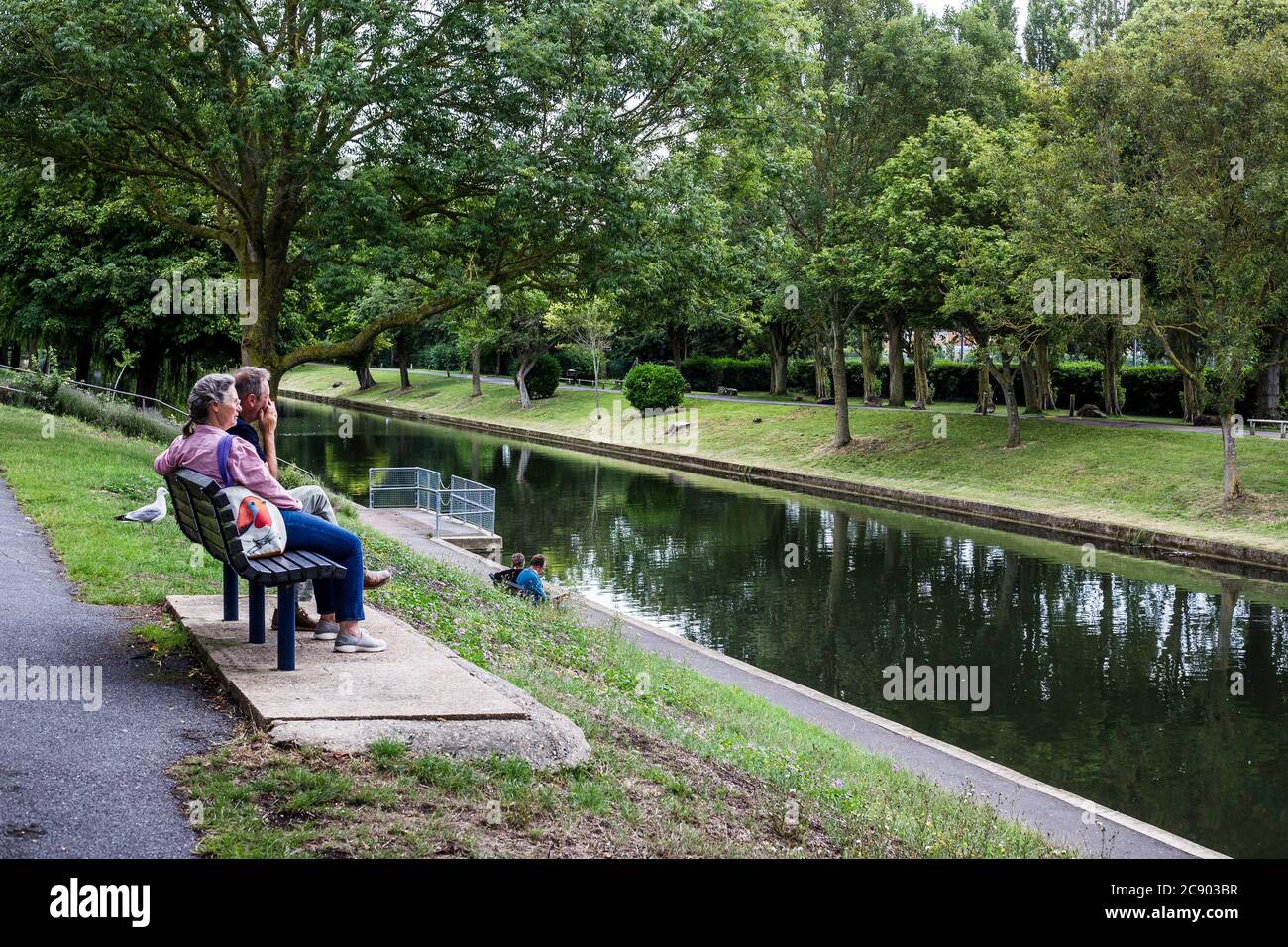 Canale militare di Hythe. Un uomo e una donna si siedono su una panchina e si rilassano a lato dell'acqua. Foto Stock