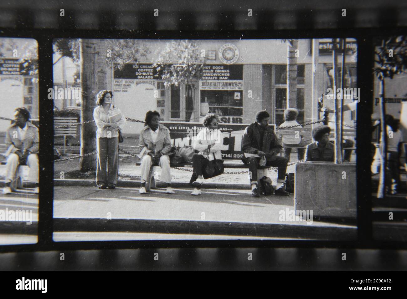 Bella fotografia in bianco e nero degli anni '70 di gente normale che aspetta l'autobus ad una fermata dell'autobus urbano. Foto Stock