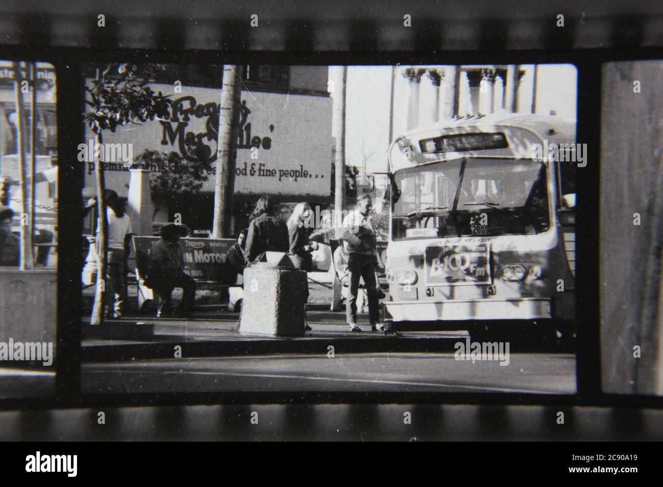 Bella fotografia in bianco e nero degli anni '70 di gente normale che aspetta l'autobus ad una fermata dell'autobus urbano. Foto Stock