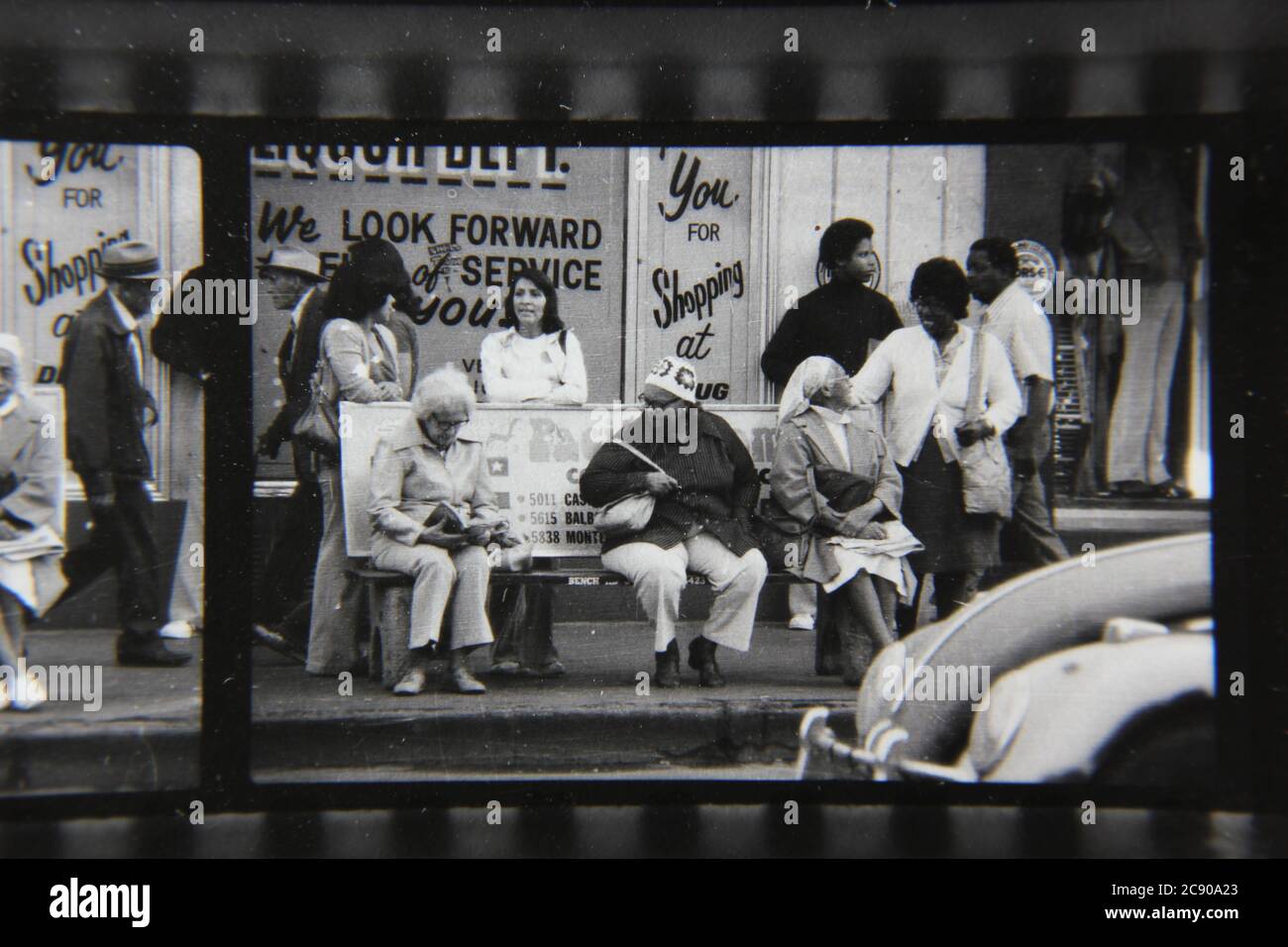 Bella fotografia in bianco e nero degli anni '70 di gente normale che aspetta l'autobus ad una fermata dell'autobus urbano. Foto Stock