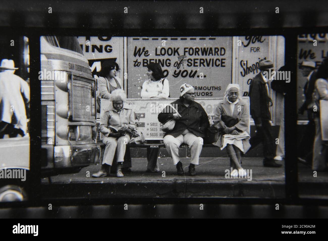 Bella fotografia in bianco e nero degli anni '70 di gente normale che aspetta l'autobus ad una fermata dell'autobus urbano. Foto Stock