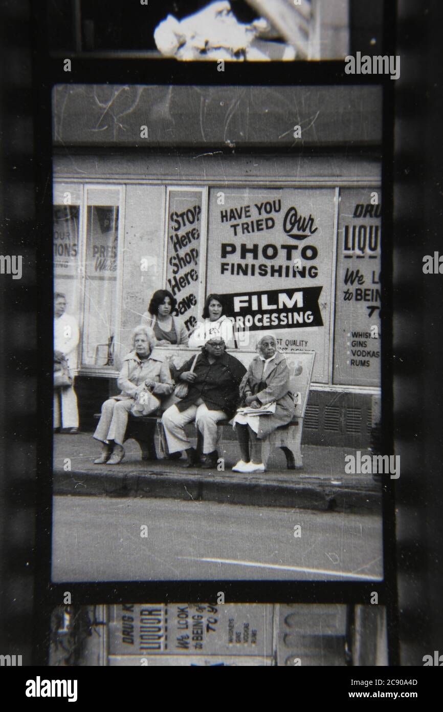 Bella fotografia in bianco e nero degli anni '70 di gente normale che aspetta l'autobus ad una fermata dell'autobus urbano. Foto Stock