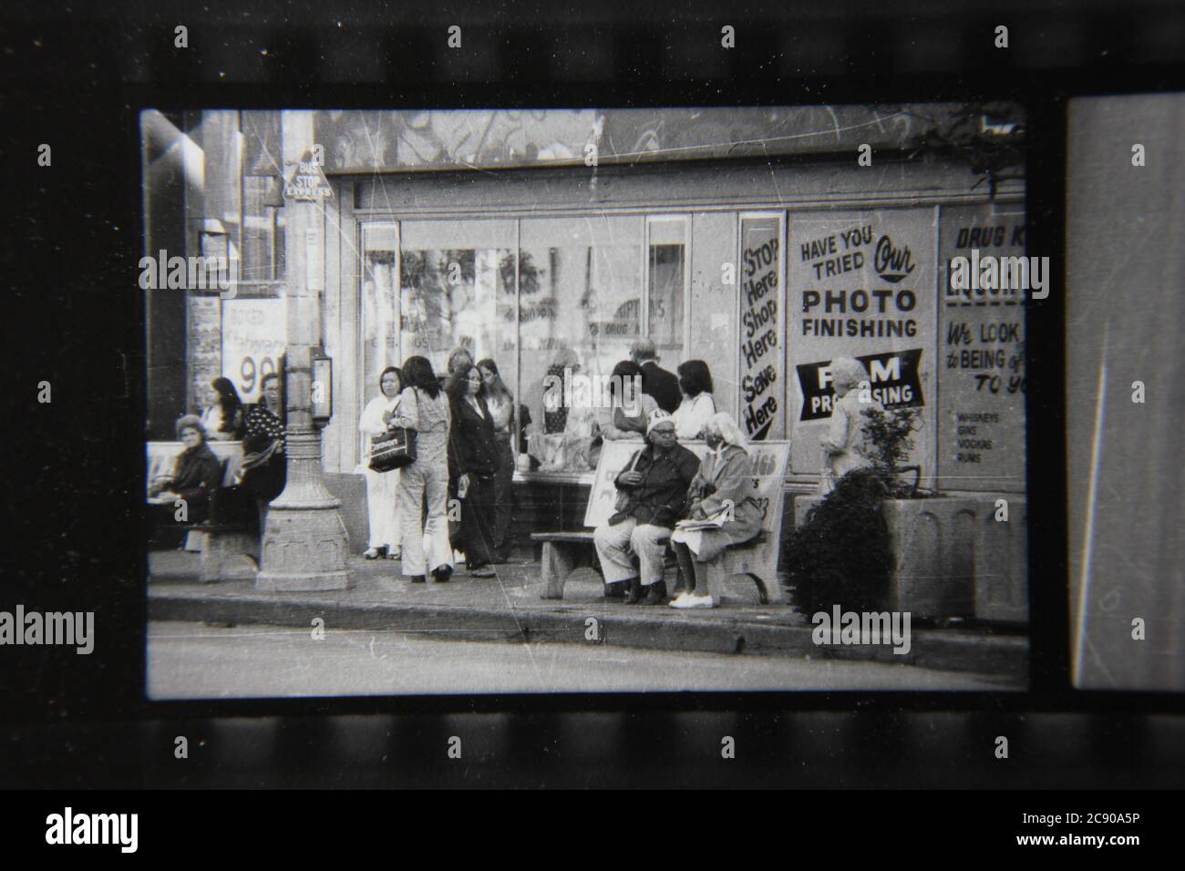 Bella fotografia in bianco e nero degli anni '70 di gente normale che aspetta l'autobus ad una fermata dell'autobus urbano. Foto Stock