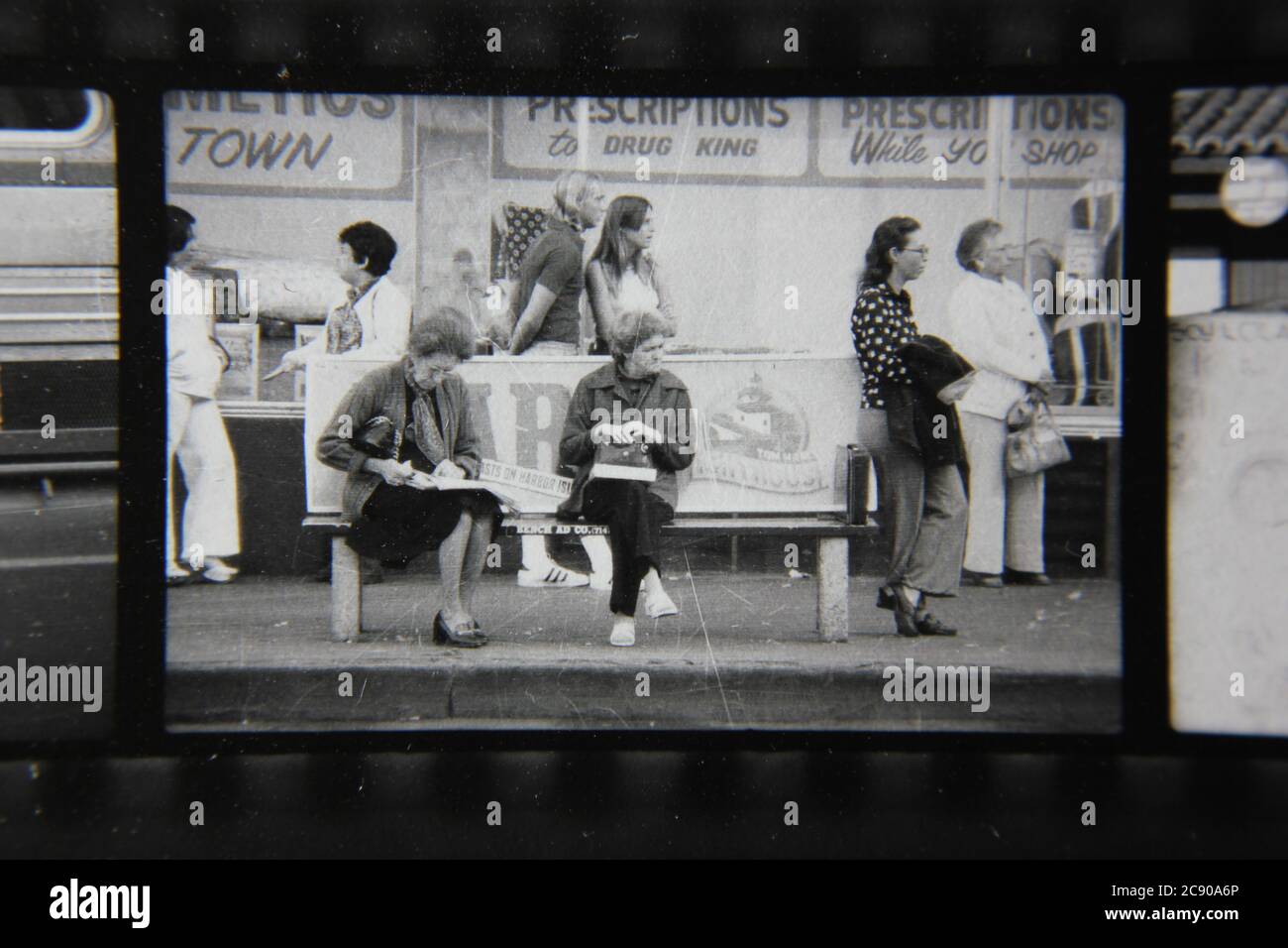 Bella fotografia in bianco e nero degli anni '70 di gente normale che aspetta l'autobus ad una fermata dell'autobus urbano. Foto Stock