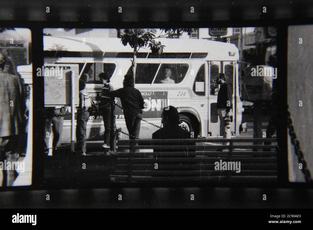 Bella fotografia in bianco e nero degli anni '70 di gente normale che aspetta l'autobus ad una fermata dell'autobus urbano. Foto Stock