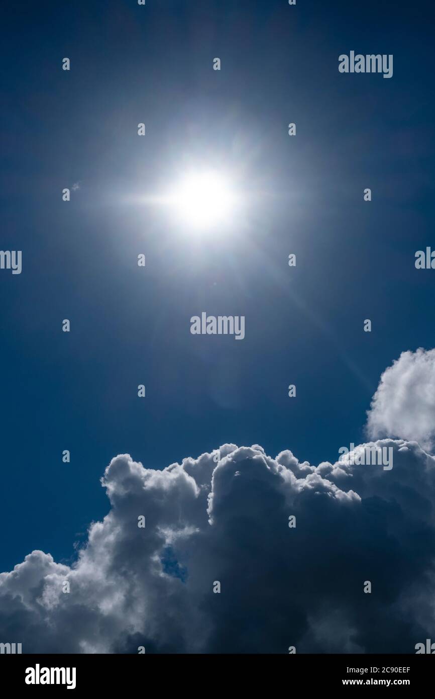 Nuvole e sole nel cielo blu Foto Stock