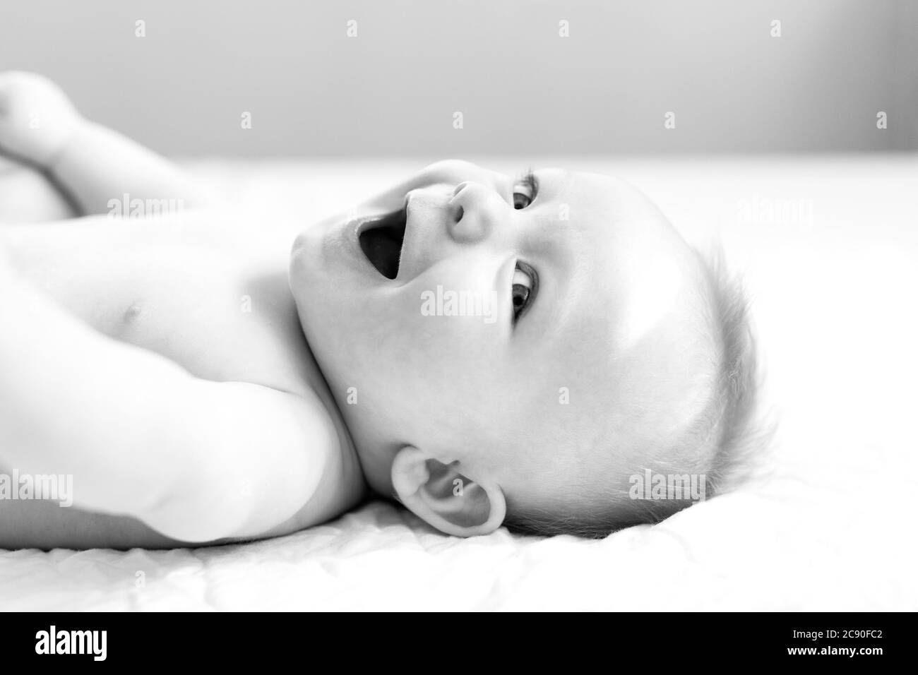 Sorridente bambino giacente sul letto Foto Stock