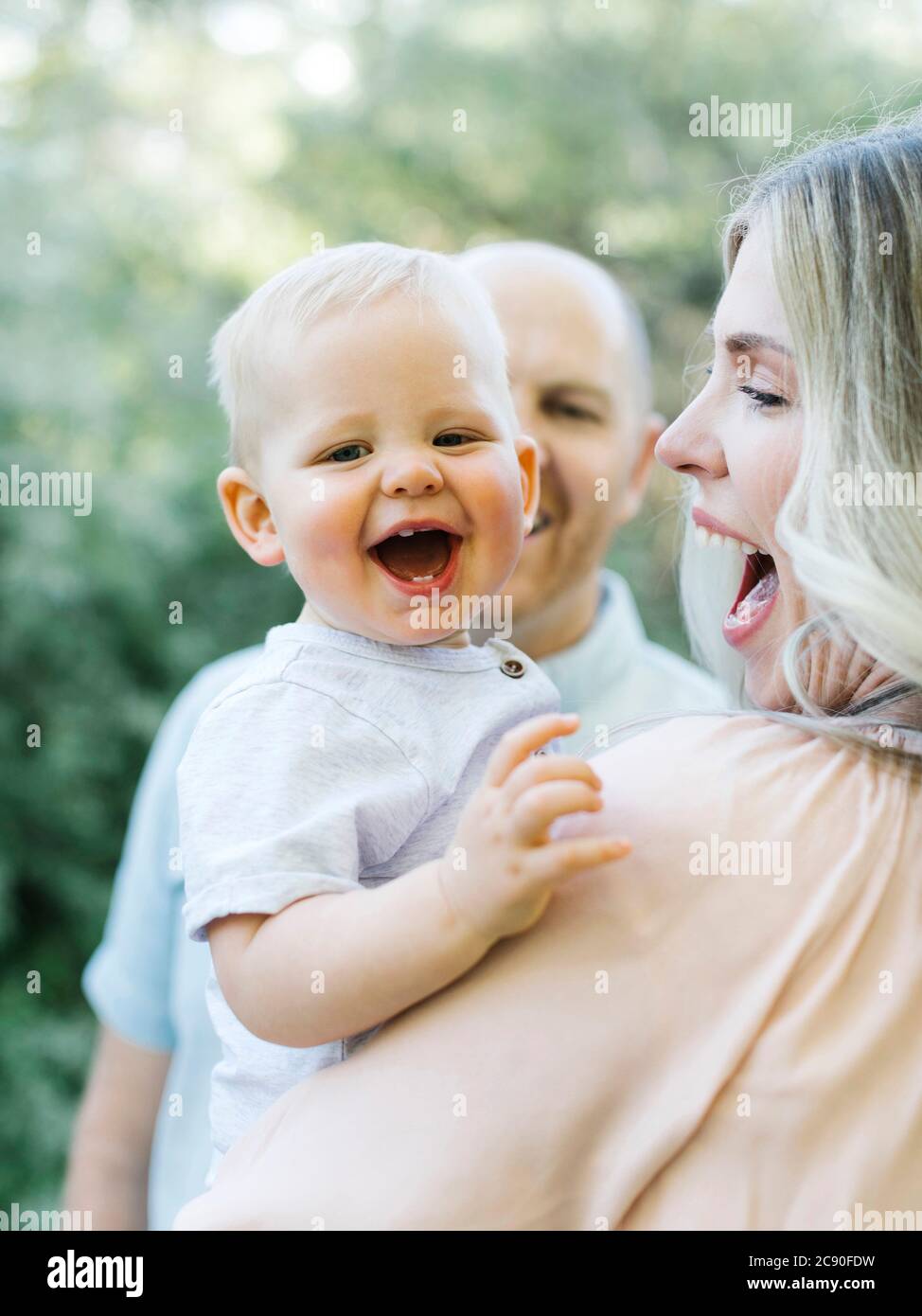 Bambino ragazzo ridendo all'aperto con i suoi genitori Foto Stock