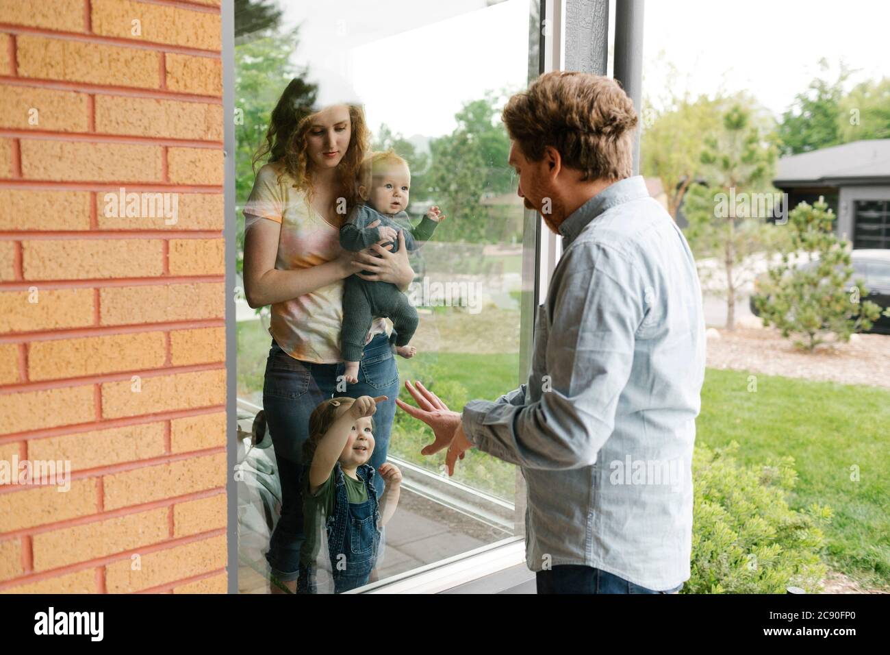 USA, Utah, Salt Lake City, il padre che visita partner e bambini (6-11 mesi, 2-3) attraverso la finestra Foto Stock