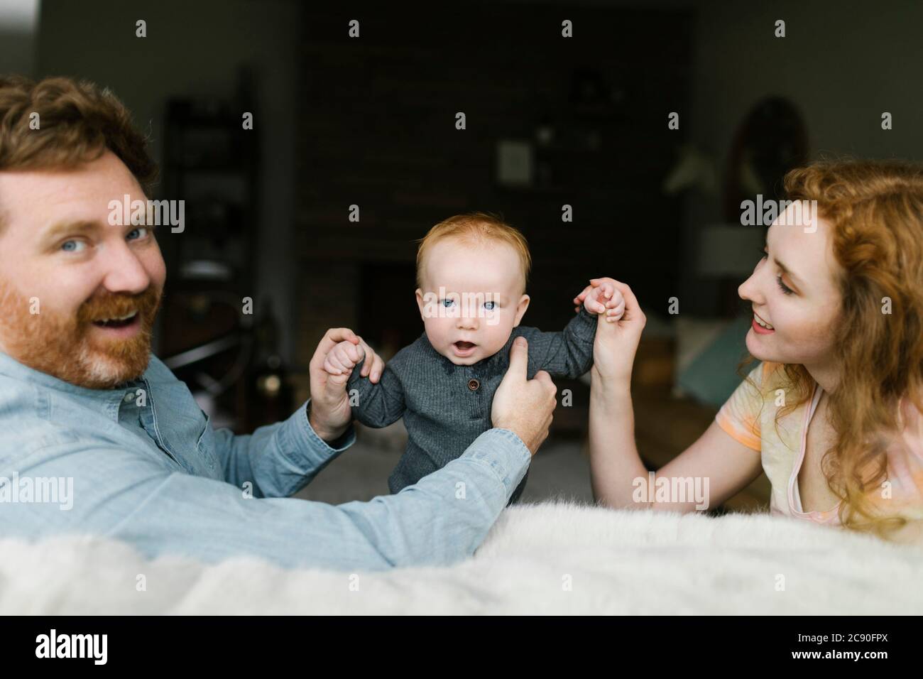 Madre e padre che detengono il figlio del bambino (6-11 mesi) Foto Stock