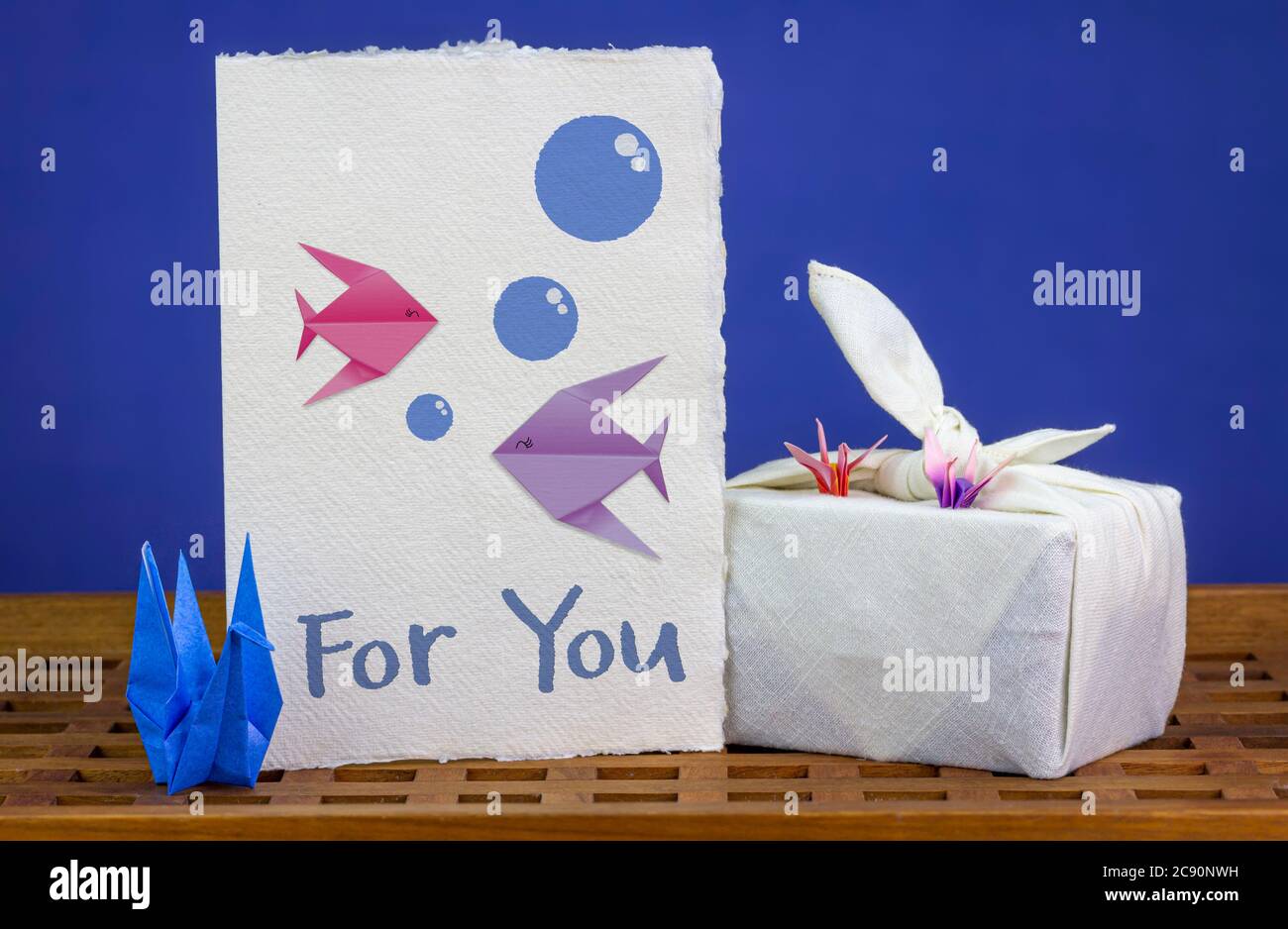 Cigni di origami fatti a mano, carta di celebrazione con pesce origami  insieme con il tessuto Furoshiki in confezione regalo, su vassoio di legno  Riusa tessuti e carta per h Foto stock -