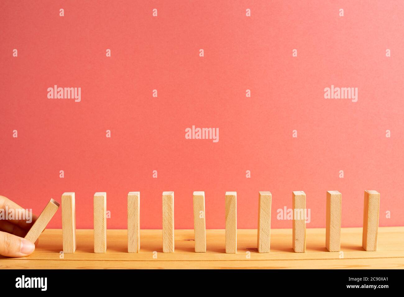 Blocchi di legno domino con sfondo rosa. Concetto di processo aziendale effetto Domino. Foto Stock