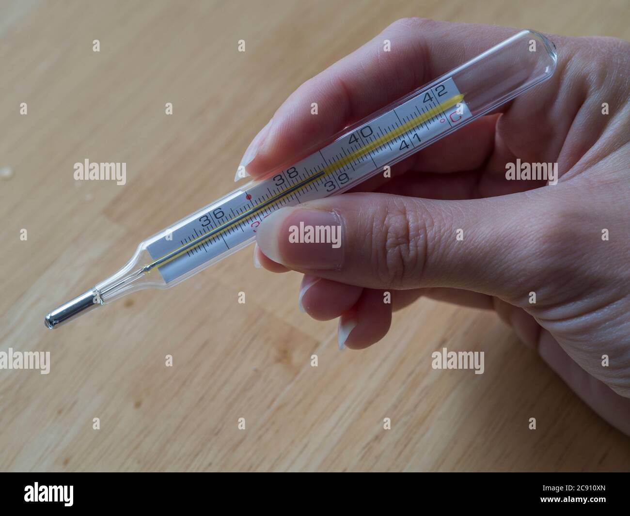 donna mano che tiene il termometro clinico di mercurio che mostra la  temperatura di febbre alta su sfondo di legno Foto stock - Alamy