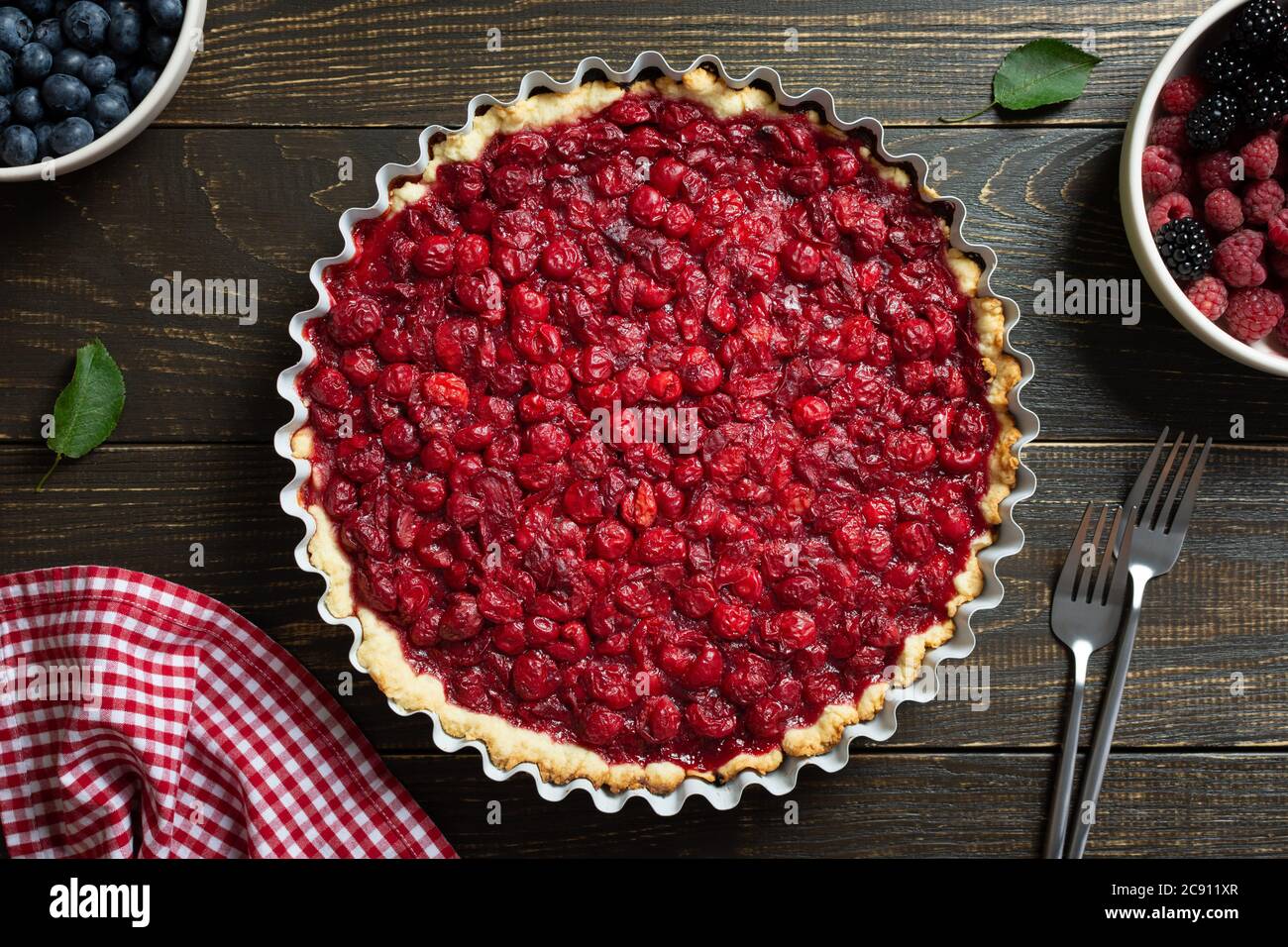 Torta aperta di pasta frolla con ciliegie, clafoutis di ciliegia su fondo di legno Foto Stock