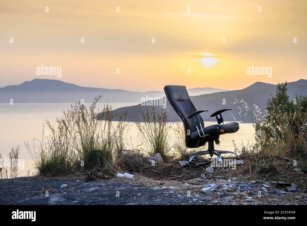 Una sedia da ufficio abbandonata in un paesaggio tramonto. Foto Stock
