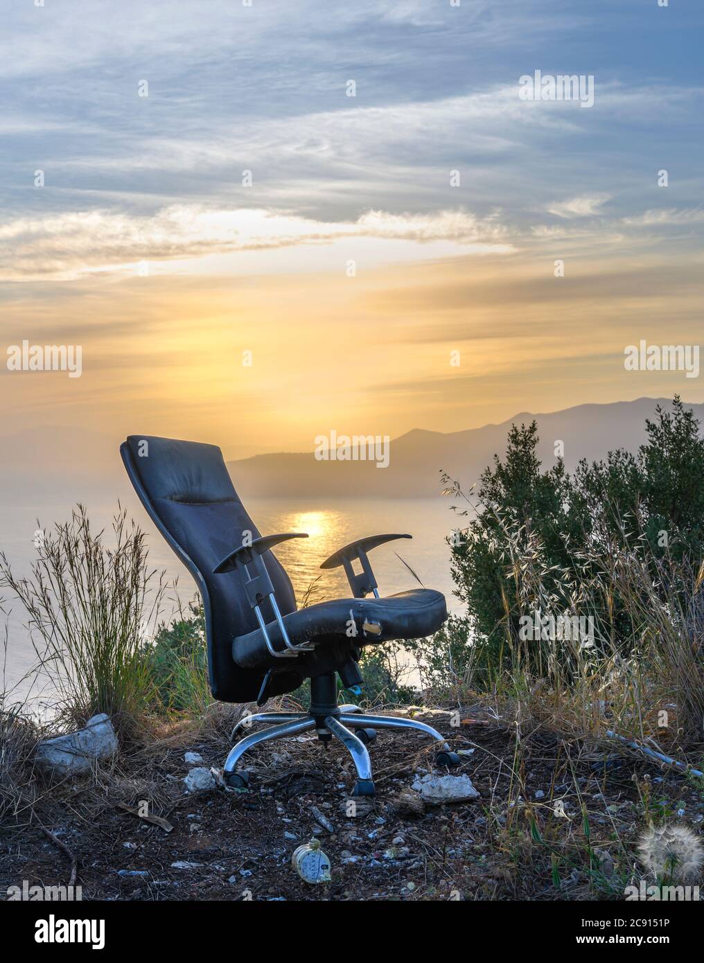 Una sedia da ufficio abbandonata in un paesaggio tramonto. Foto Stock