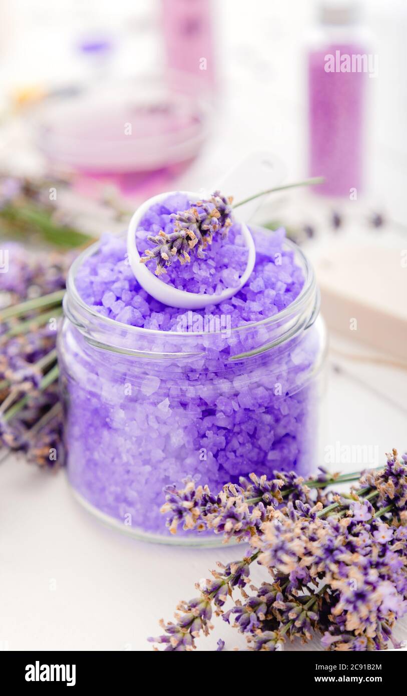Sale di mare viola di lavanda con fiori di lavanda. Prodotti da bagno alla lavanda trattamento aromaterapico su sfondo di legno bianco. Bagno di bellezza con vasca idromassaggio per la cura della pelle Foto Stock