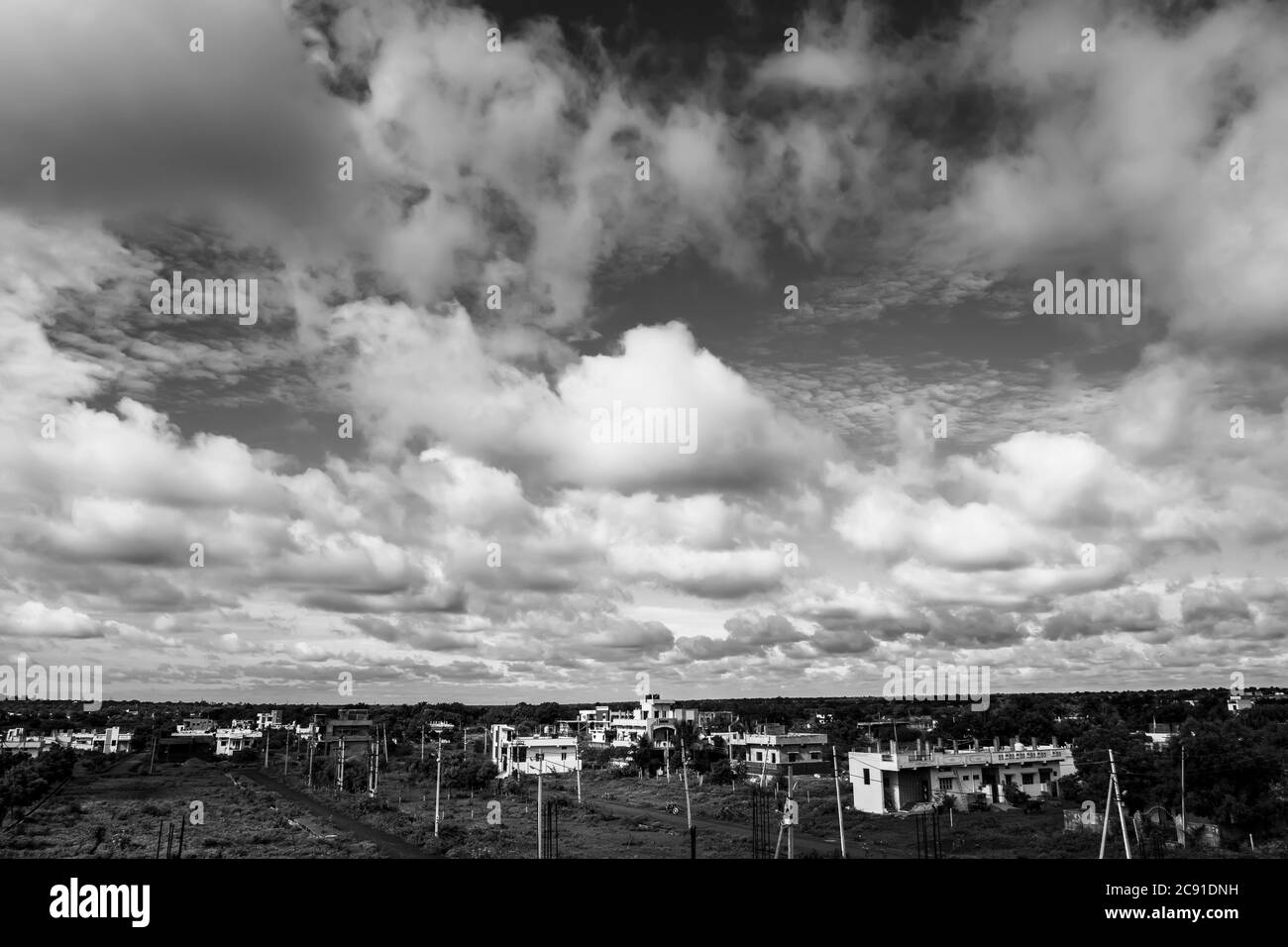 un'immagine in bianco e nero di paesaggio urbano con cielo, nuvole e terra Foto Stock