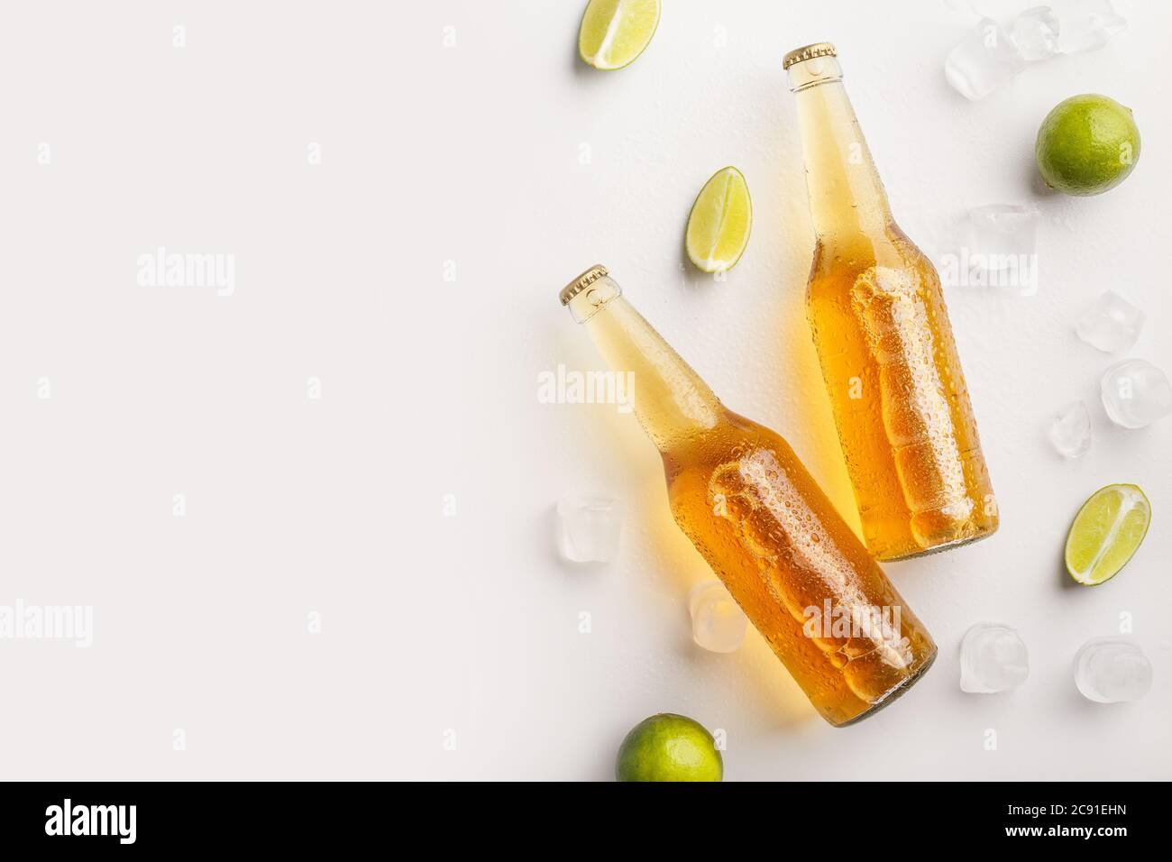 Rinfrescatevi e bevete in estate. Bottiglie con birra in ghiaccio e pezzi di lime su sfondo bianco Foto Stock
