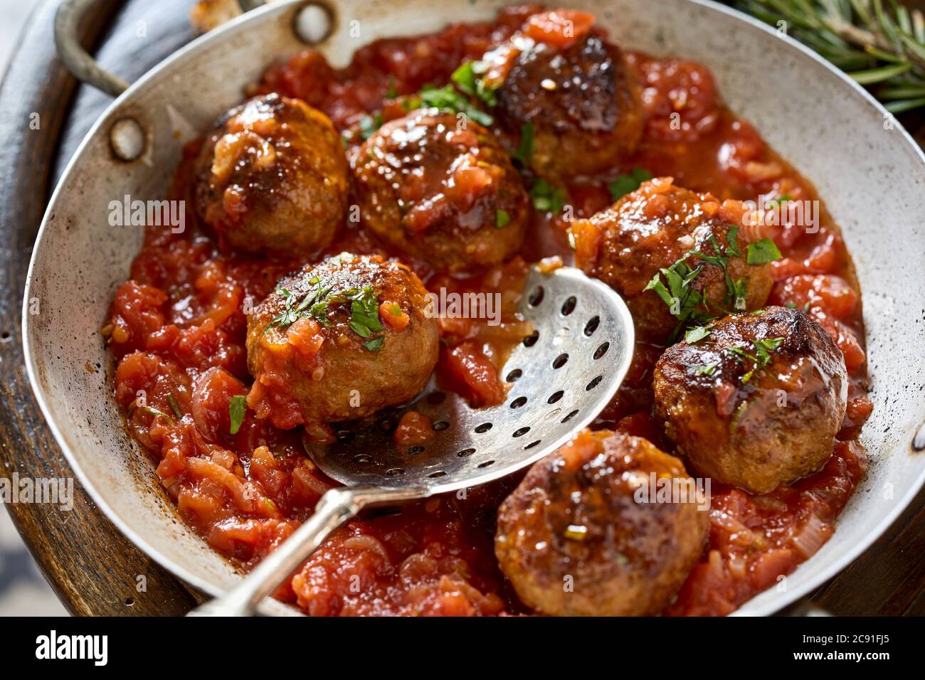 Ricetta rustica spagnola locale per polpette piccanti in un vecchio piatto di metallo con salsa a base di pomodoro ed erbe fresche in primo piano Foto Stock