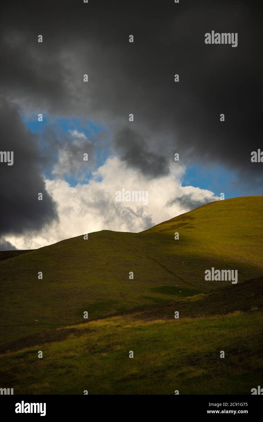 Il cielo blu e le nuvole tempeste sulle colline nella campagna scozzese quando il tempo cambia Foto Stock