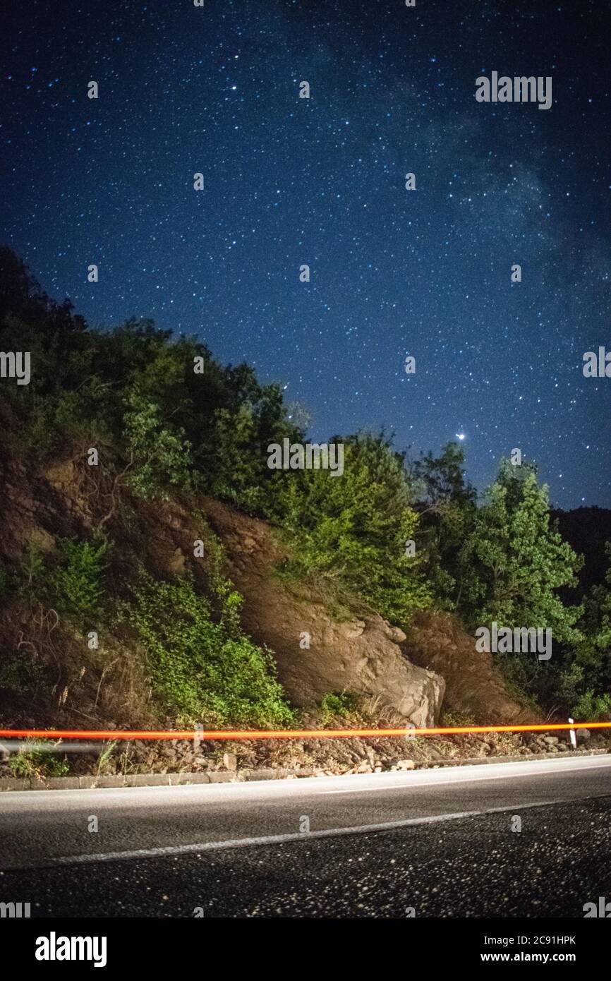 Lunga esposizione, percorsi di luce in rapido movimento in autostrada, con strade lattose e stelle Foto Stock
