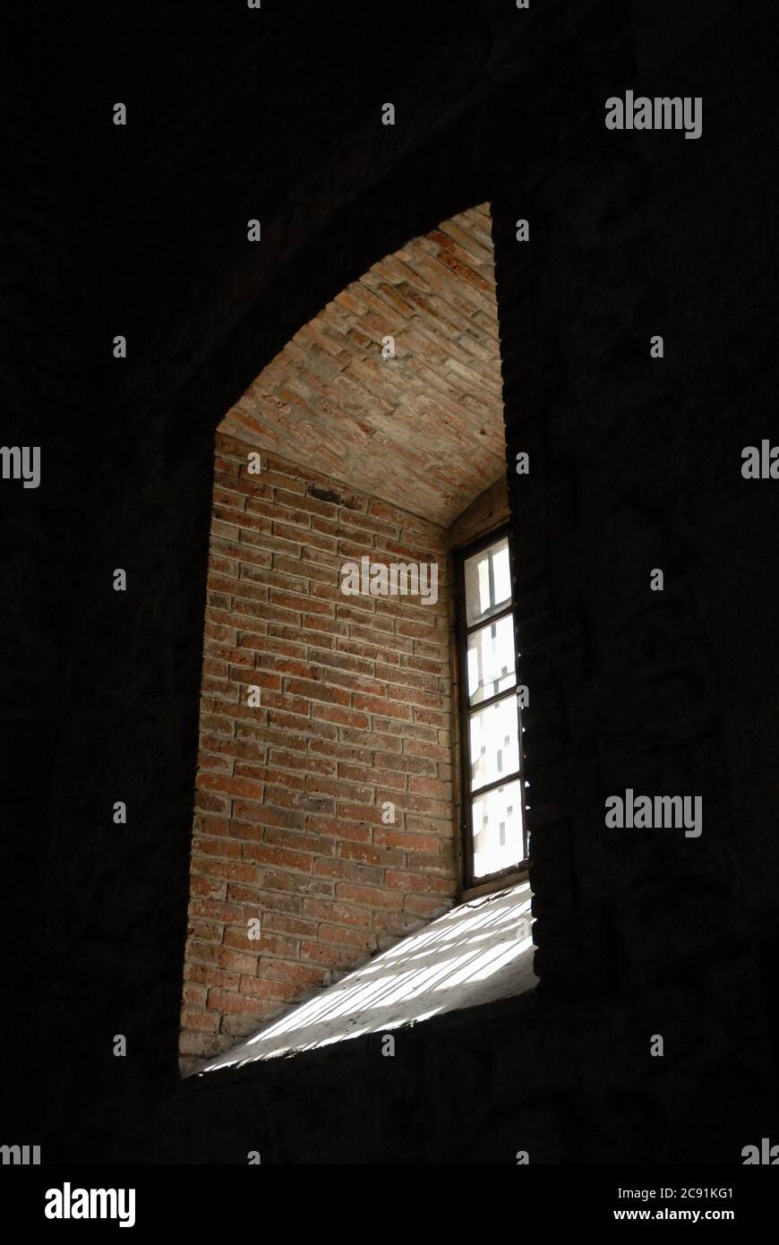 Immagine verticale di luce proveniente da una finestra in una foro muro di pietra Foto Stock